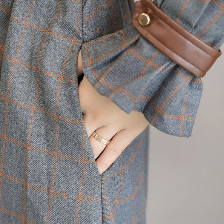 Gray checkered coat with a brown leather pocket on a neutral background